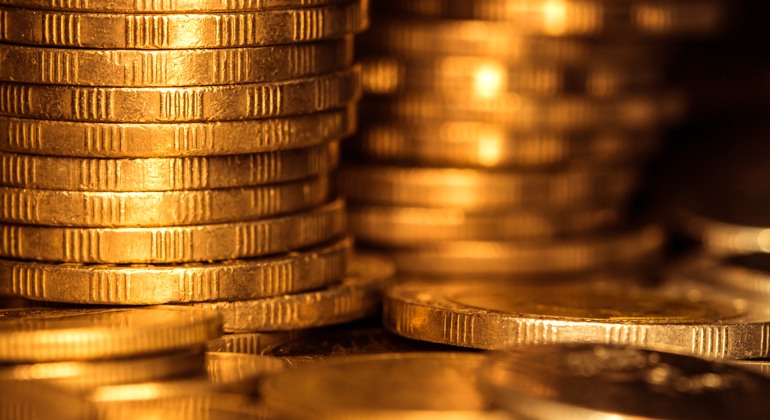 Guldpengar som är staplade i högar.